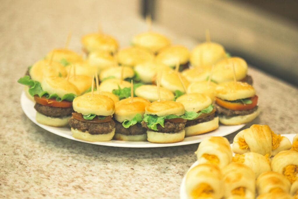 Delicious mini burgers with lettuce, tomato, and pastries perfect for parties and gatherings.