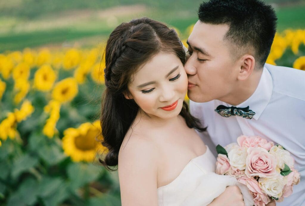 Bride and groom share a loving moment in a sunflower field during their wedding.