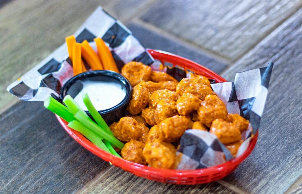 Crispy buffalo cauliflower paired with carrots, celery, and ranch dip in a vibrant basket.