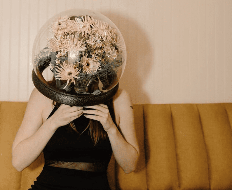 A woman in a black dress wears a flower-filled dome, blending nature and futurism.