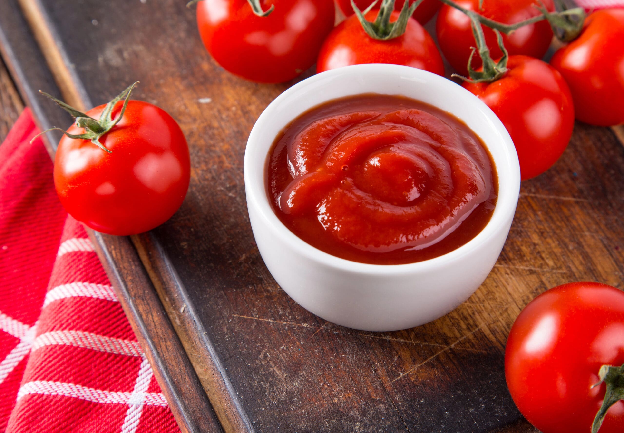 Bowl of tomato sauce and cherry tomatoes on wooden table.