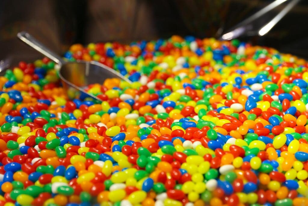 Vibrant selection of colorful jelly beans with a scoop at a candy store, bursting with sweetness.