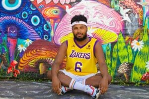 Man sitting against a vibrant mural wearing a Lakers jersey in São Paulo, Brazil.