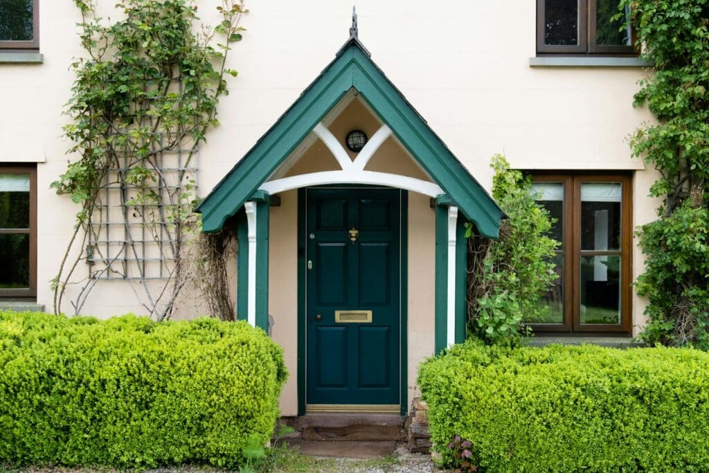 Quaint cottage entrance with green door and ivy in Hereford, England.