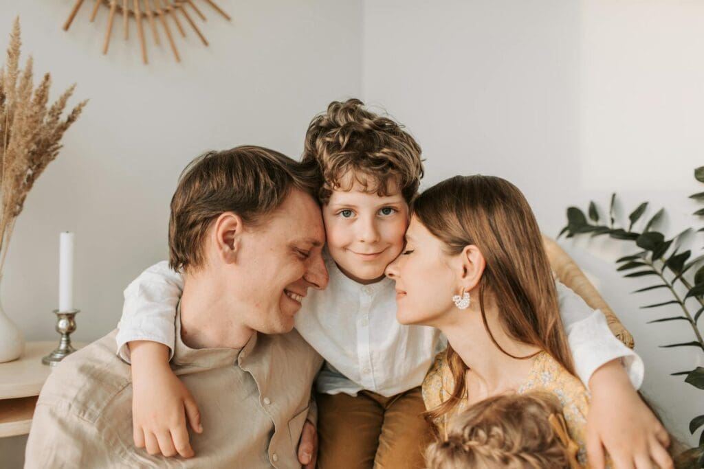 A joyful family moment with parents and their son embracing indoors.