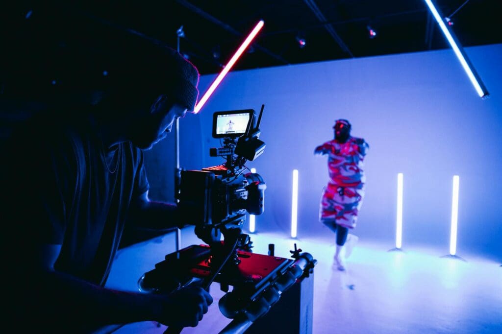 Behind-the-scenes look at a studio shoot with neon lights and camera crew.