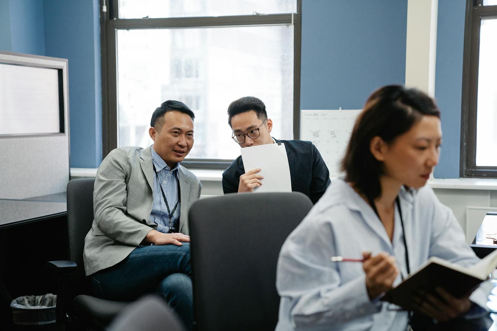 Colleagues whispering during work in an office setting, signaling teamwork and collaboration.