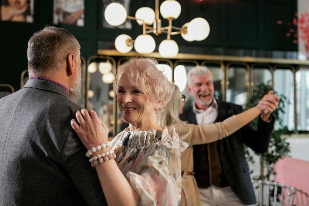 Joyful elderly couples dancing indoors, celebrating togetherness and romance.