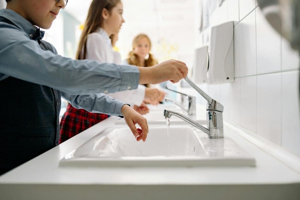 Kids washing hands at school sink promoting hygiene and health in educational setting.