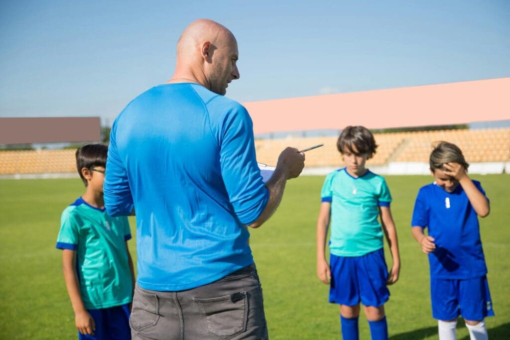 A coach instructs a group of young boys during a soccer practice on a sunny day.