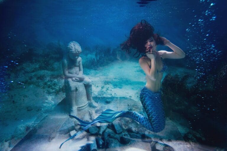 A captivating shot of a mermaid underwater near a statue in Barcelona, Spain.