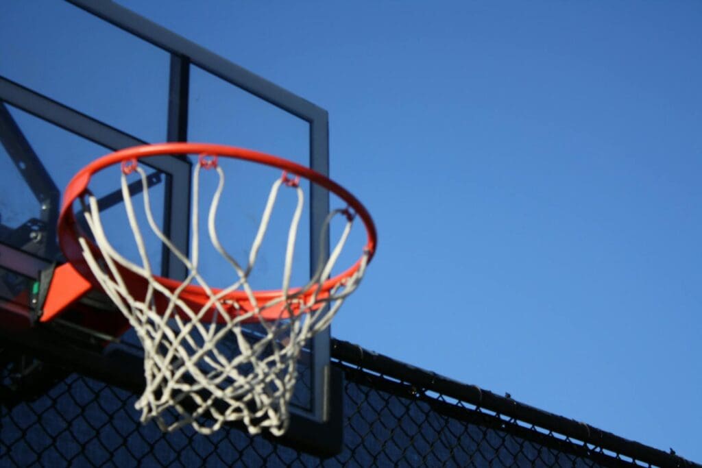A vibrant outdoor basketball hoop with net set against a clear blue sky, ideal for sports visuals.