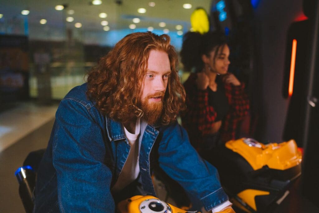 A couple engrossed in playing arcade games indoors, exuding joy and togetherness.