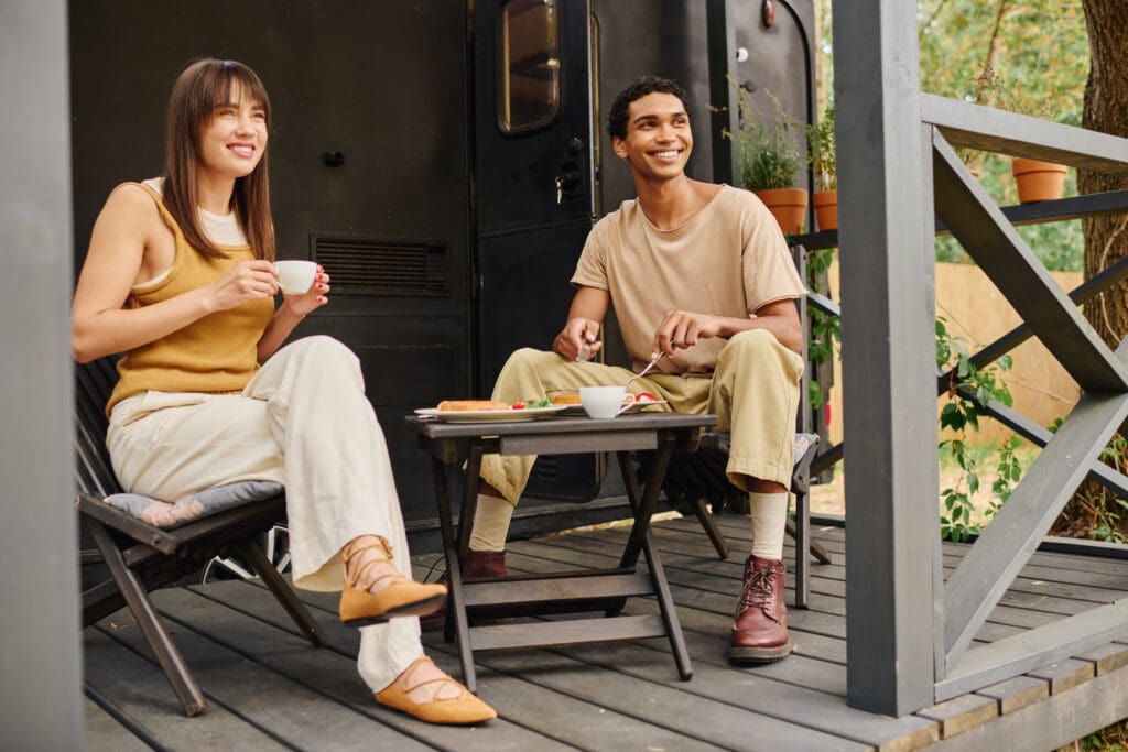An interracial couple relaxes together on a cozy porch, enjoying each others company in a peaceful setting.