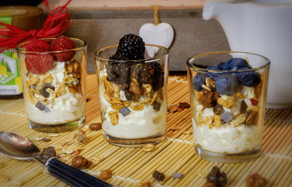 Three glasses of yogurt topped with different fruits