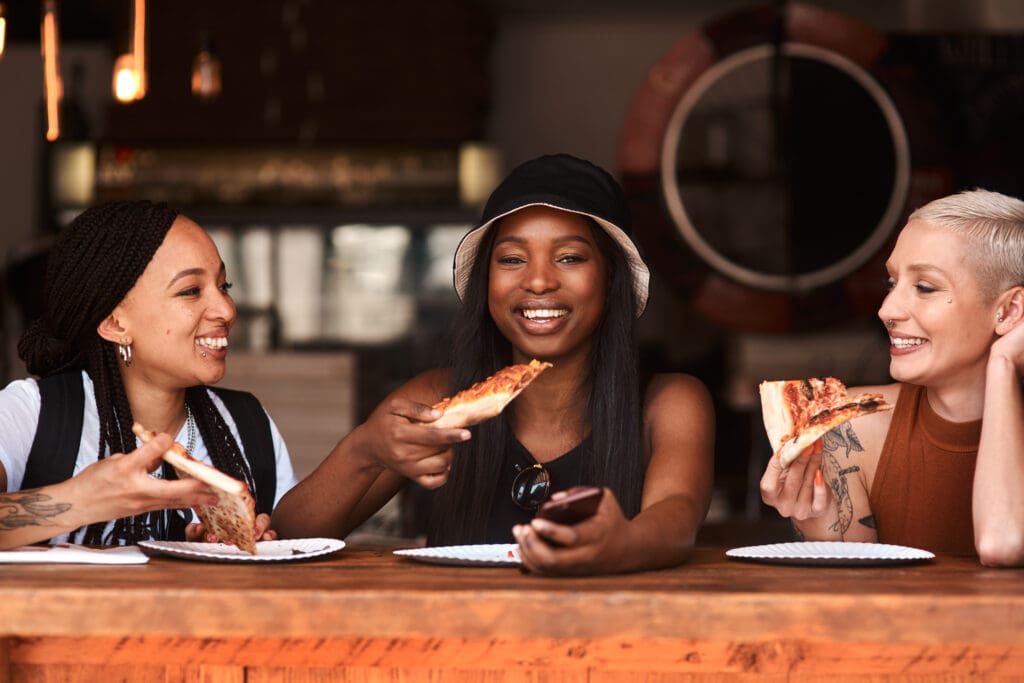 Cropped shot of friends having pizza at a cafe together.
