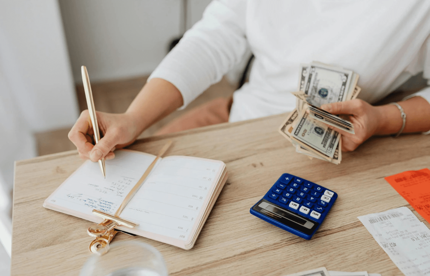 Person budgeting with calculator and cash in hand