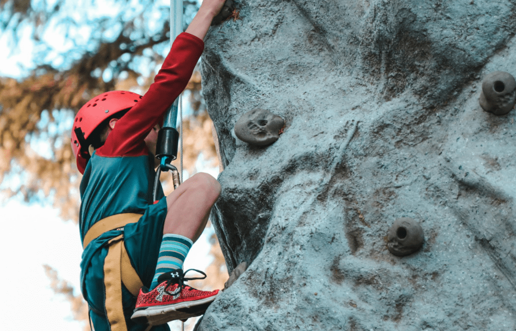 Student rock climbing while wearing safety helmet