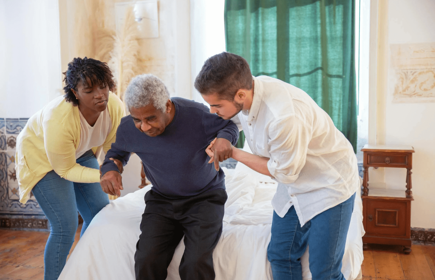 Elderly man receiving support from two caregivers