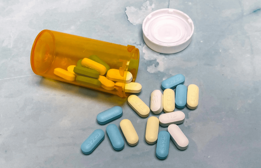 Yellow bottle of antibiotics with scattered pills