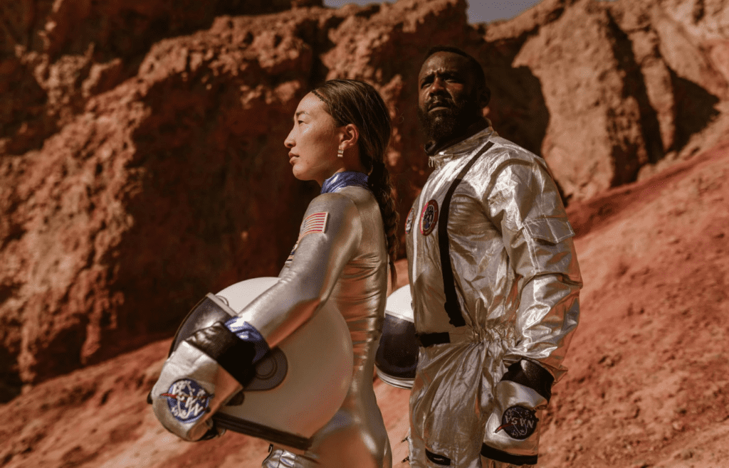 Astronauts holding helmets on Martian landscape