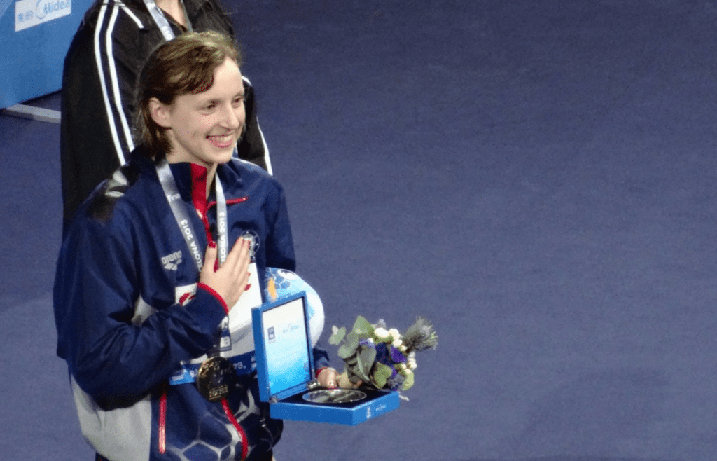 Katie Ledecky is wearing a prize and a medal in her hand