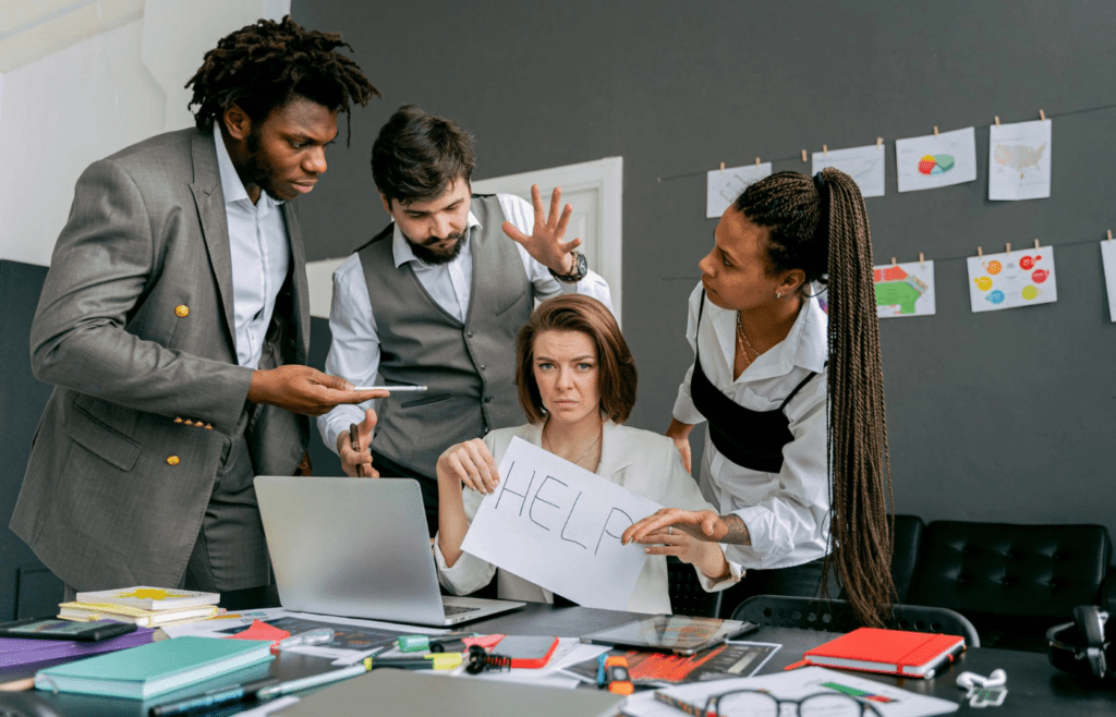Woman holding help sign as coworkers ignore