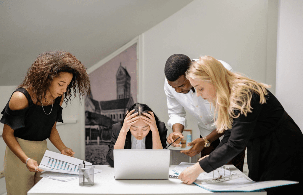 Stressed employee surrounded by negative coworkers at work