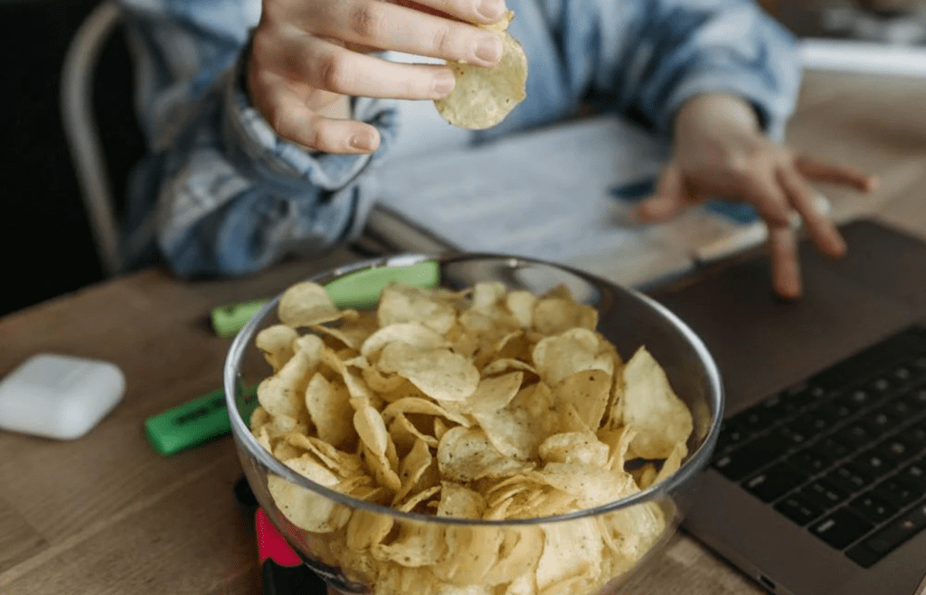 A person stress-eating chips or candy at their desk