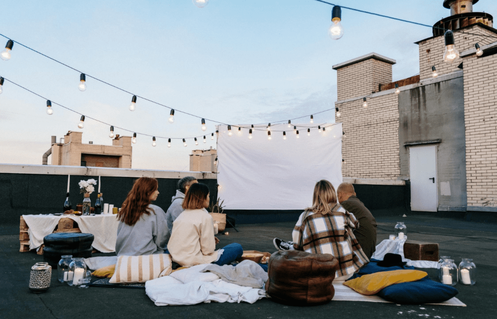 A projector screen set up outdoors with blankets and pillows