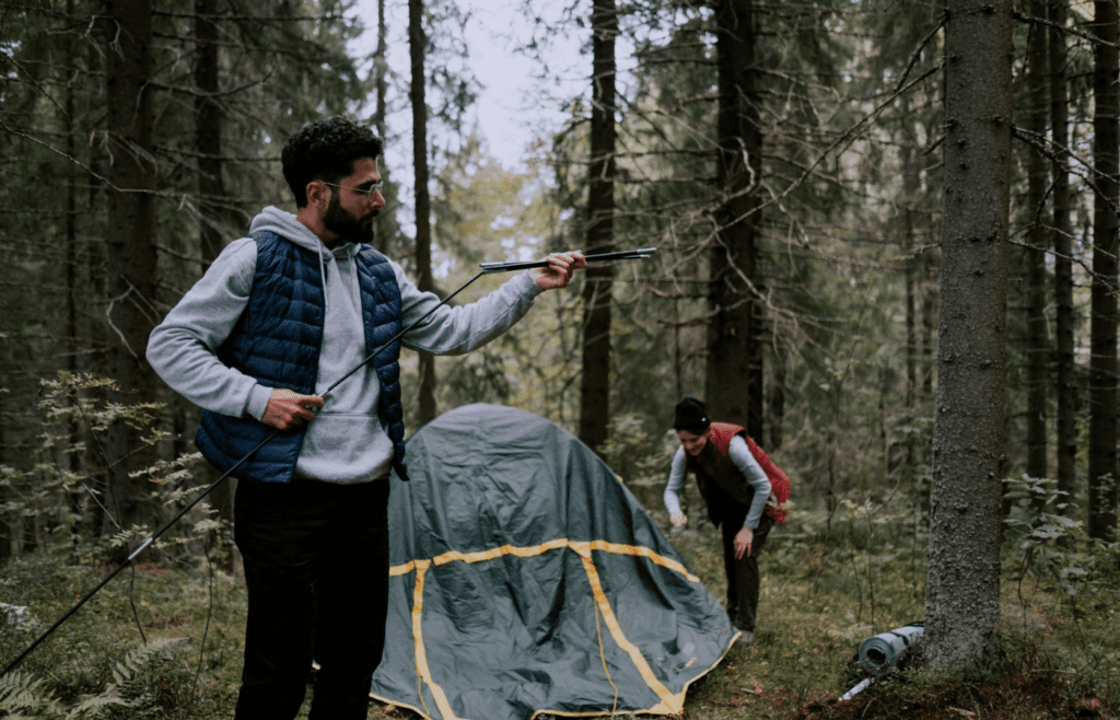 A person setting up a tent in a forest clearing