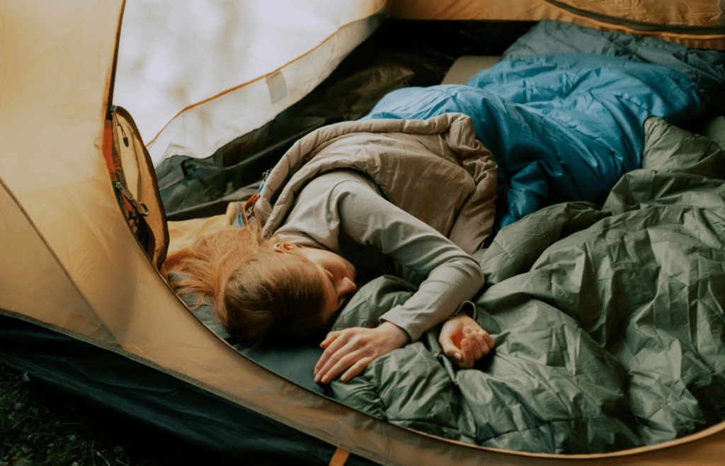 A person inflating a sleeping pad by their tent