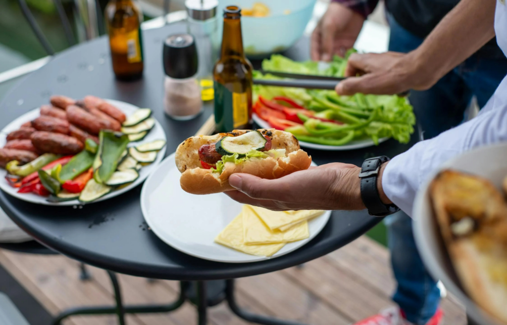 Sausages and colorful peppers grilling side-by-side