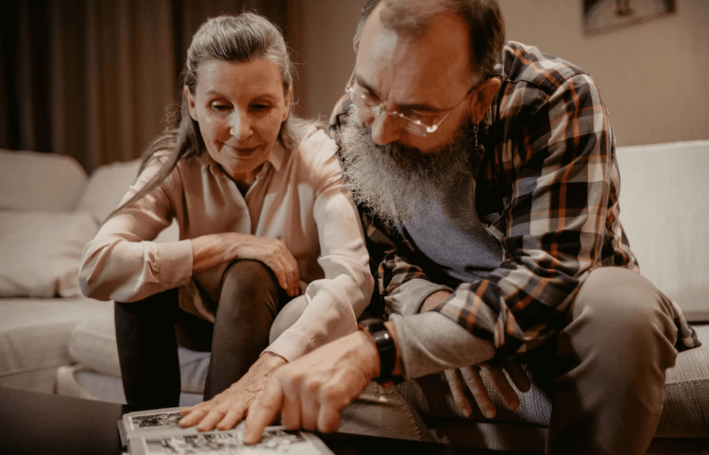 A couple smiling, surrounded by old photos or memories