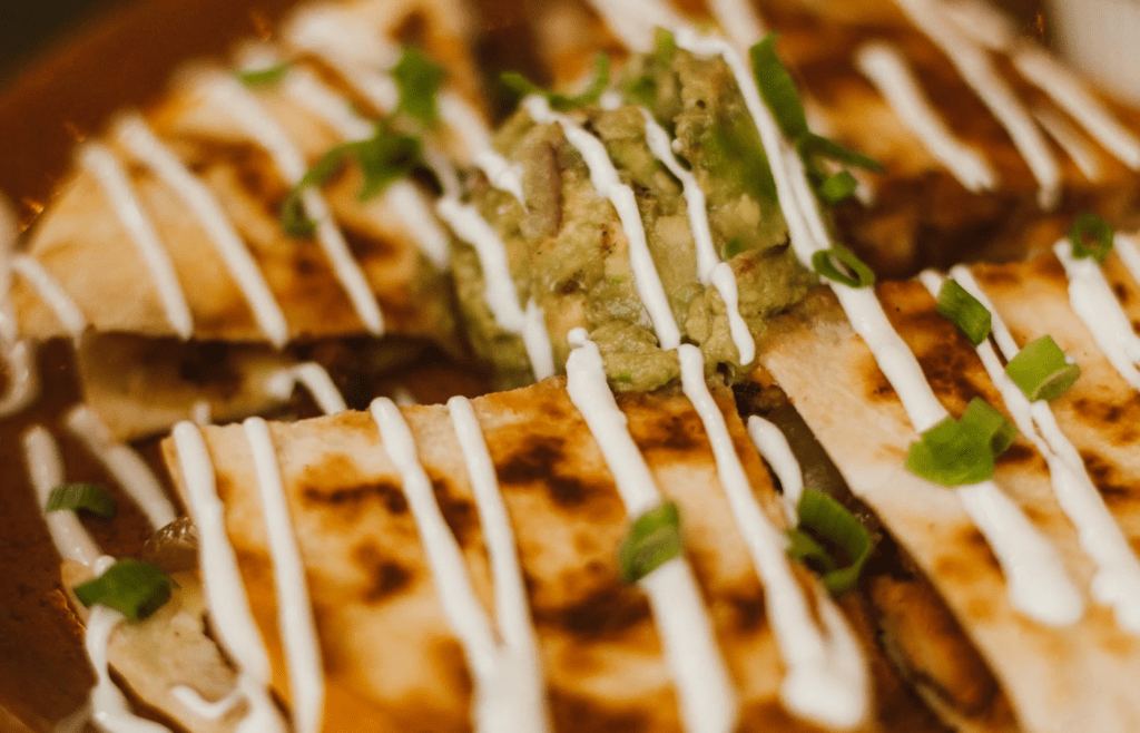 Melty cheese quesadillas being flipped on a grill