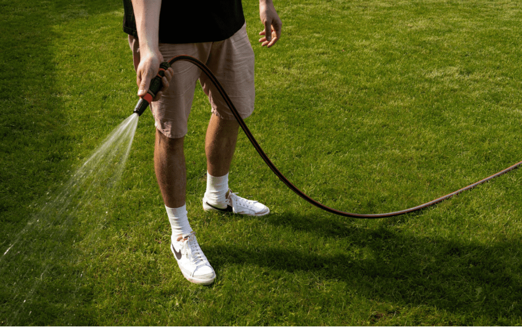 A person turning on an outdoor hose bib