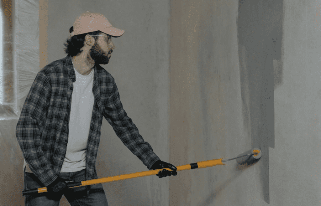 A person painting trim or siding with a brush