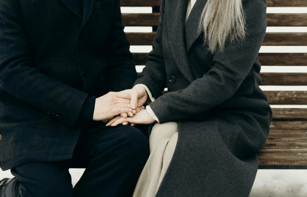 A couple sitting close, holding hands during a tough moment