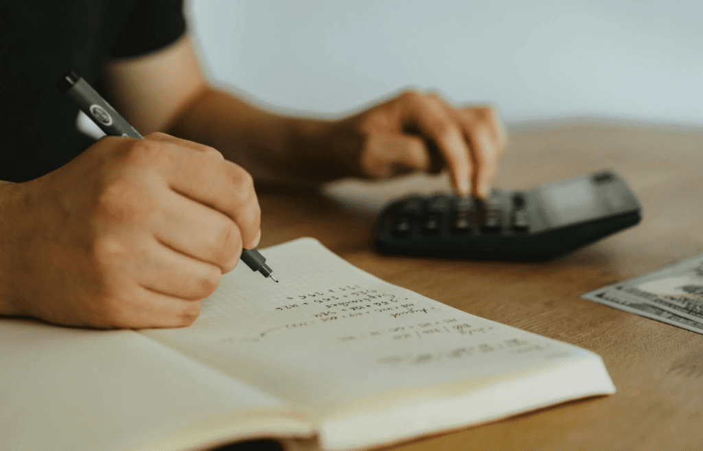 A traveler noting expenses in a small notebook