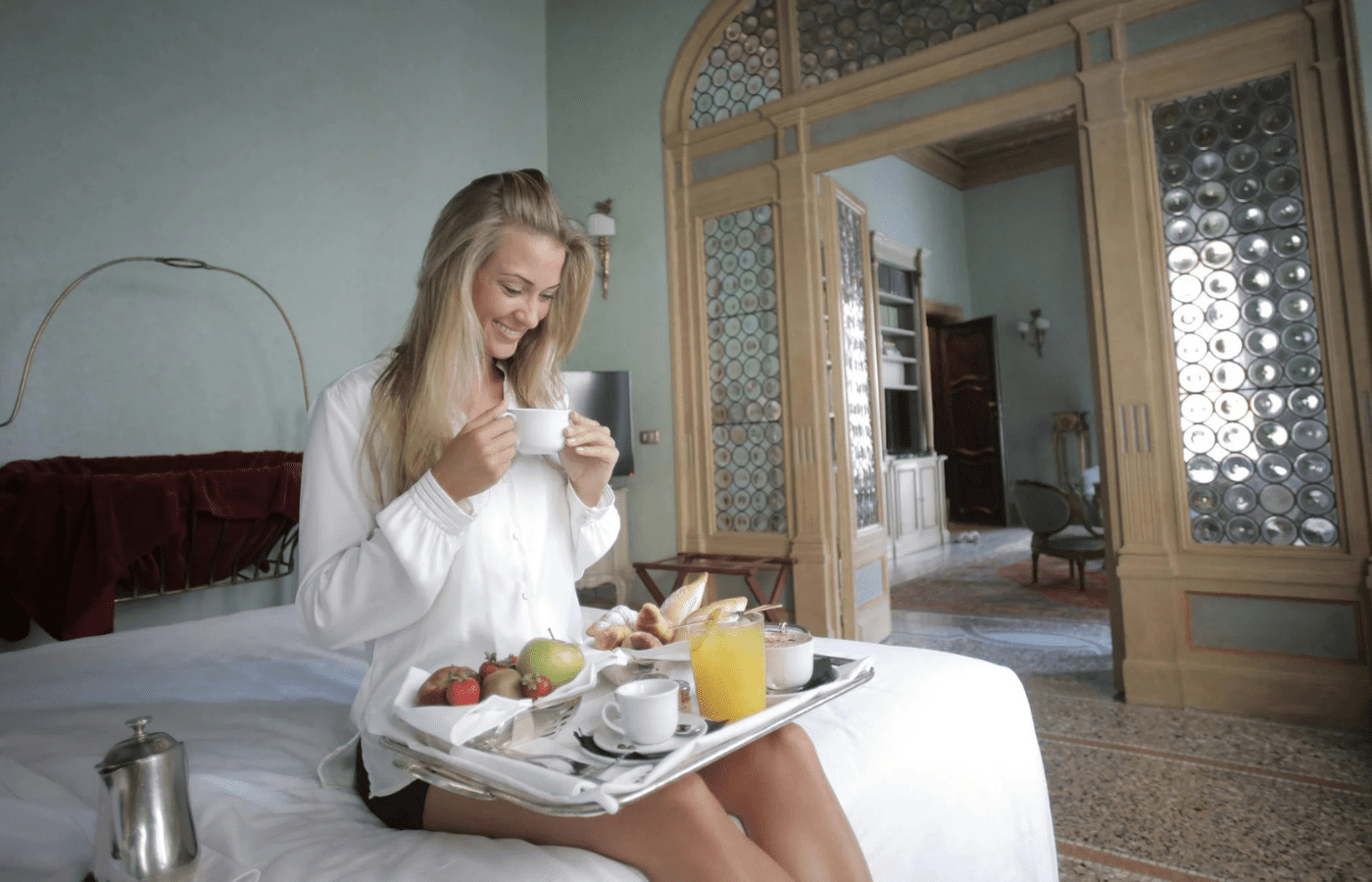 A breakfast tray on a hotel bed with fresh coffee