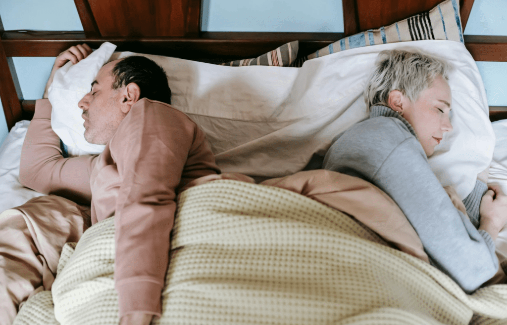 A couple lying back to back in bed