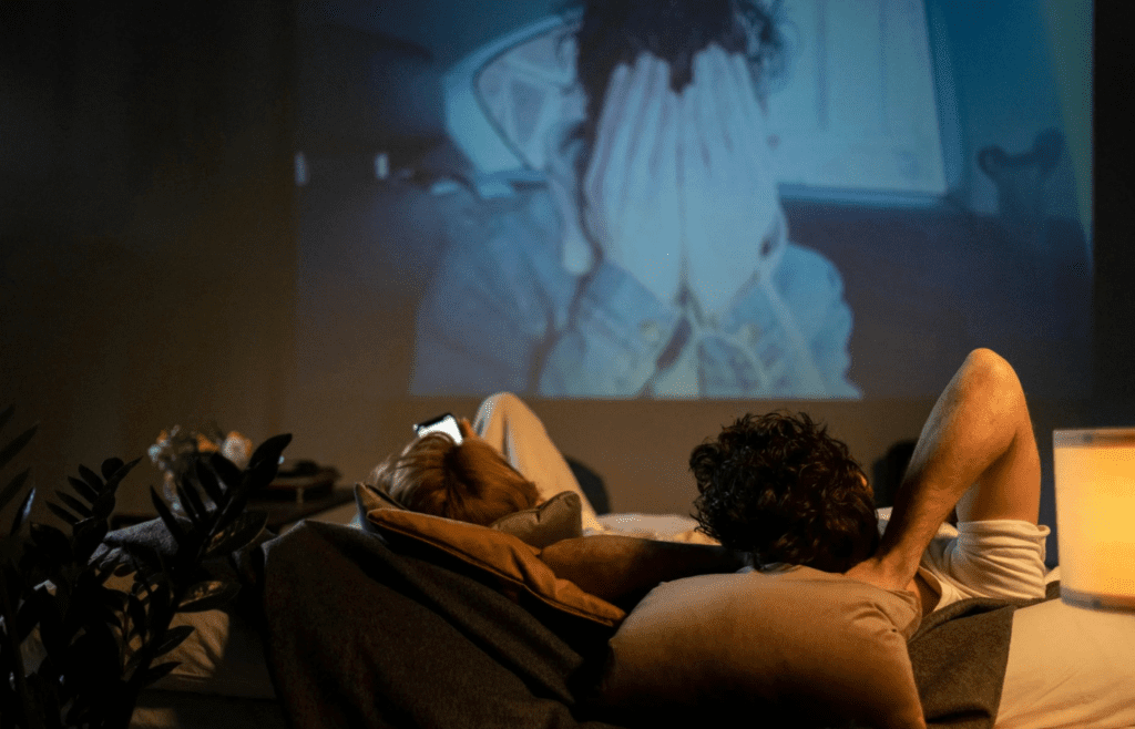 A couple cuddled up watching a movie at home