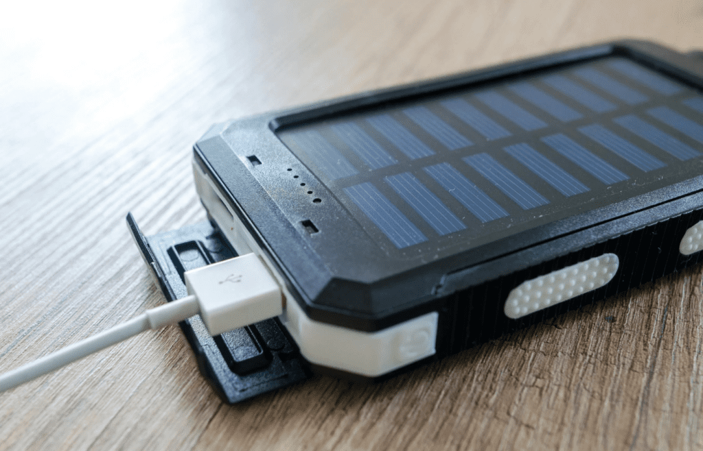 A traveler plugging a phone into a slim portable charger