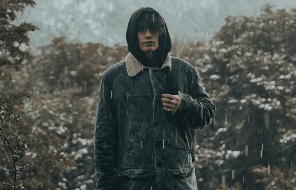A traveler slipping on a compact rain jacket outdoors