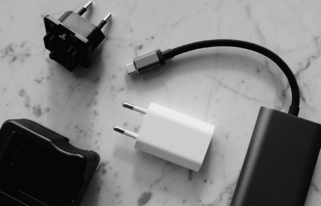 A multi-country plug adapter next to a phone charger
