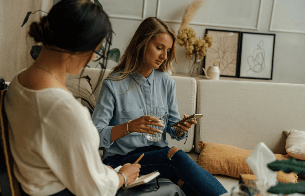 A couple staring at separate phones on the couch