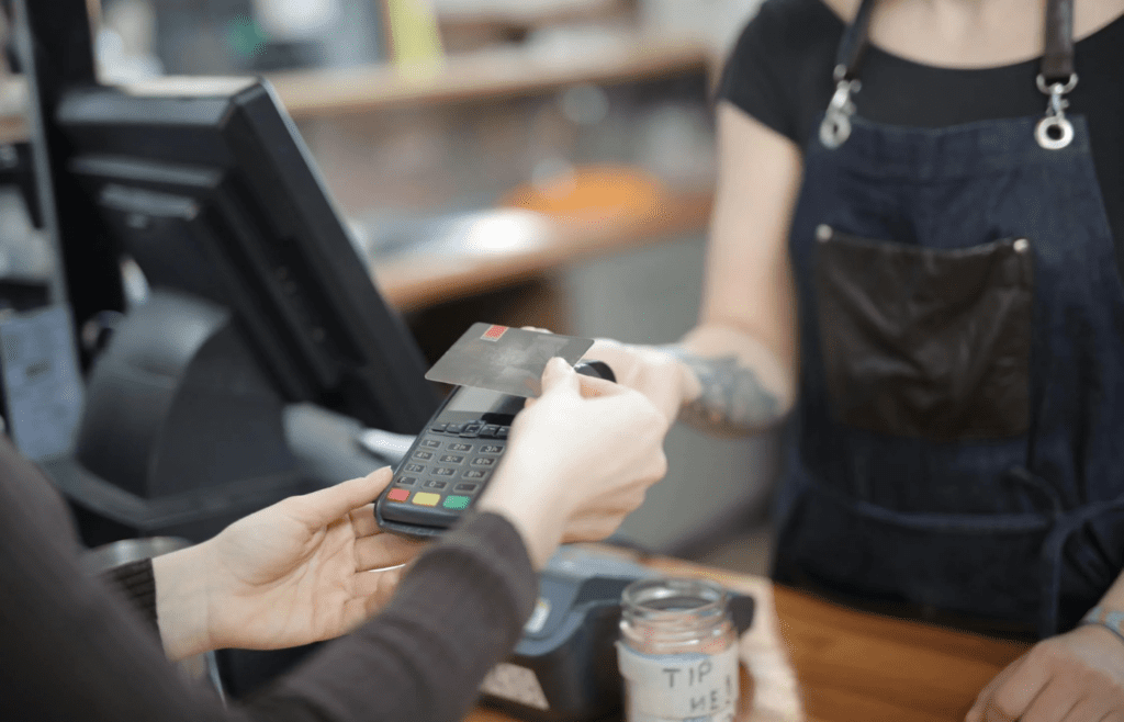 A person nervously handing over a credit card at a sales counter