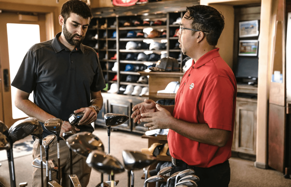 A person trying on a product with a salesperson beaming nearby