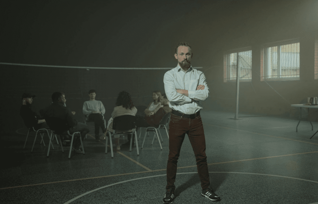 A person standing apart from a group, arms crossed