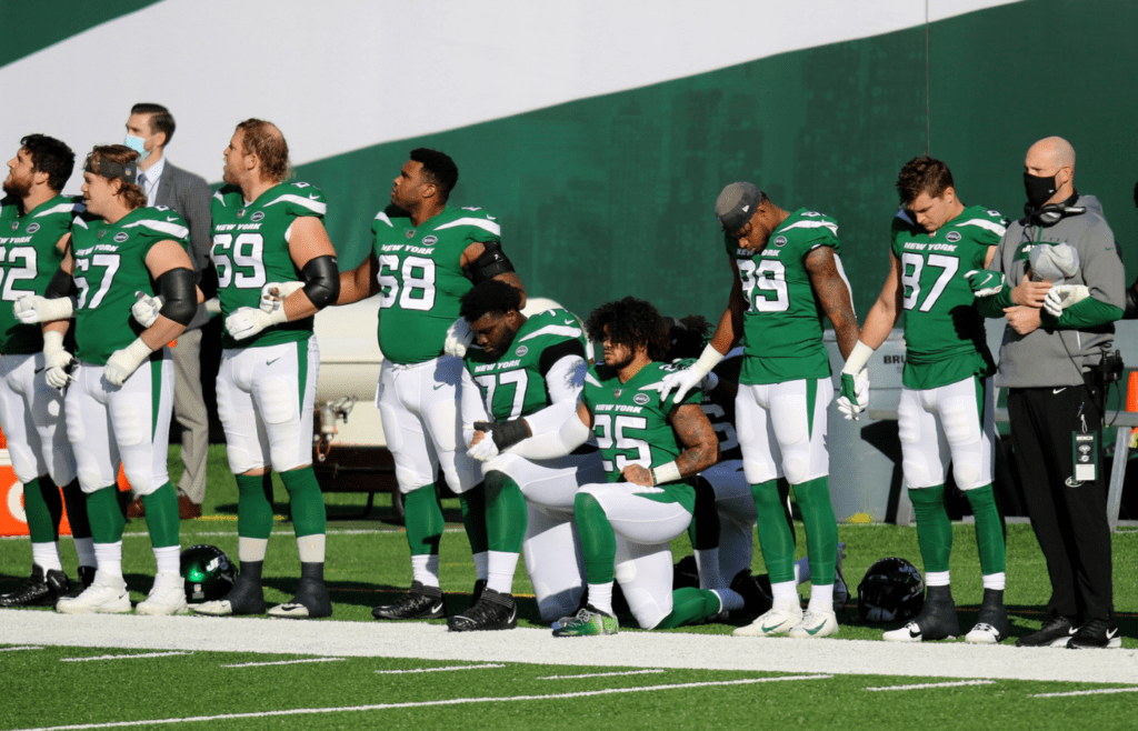 Nov 29, 2020; East Rutherford, New Jersey, USA; New York Jets offensive tackle Mekhi Becton (77) and cornerback Nate Hairston (25) kneel during the National Anthem before a game against the Miami Dolphins at MetLife Stadium. Mandatory Credit: Kevin Wexler-Imagn Images